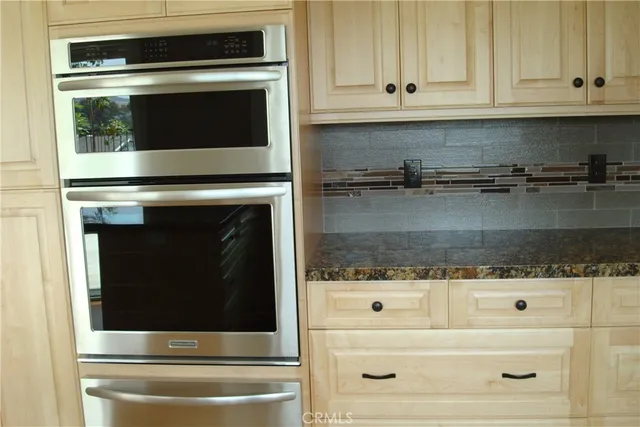 a bathroom with granite countertop white cabinets and stainless steel appliances