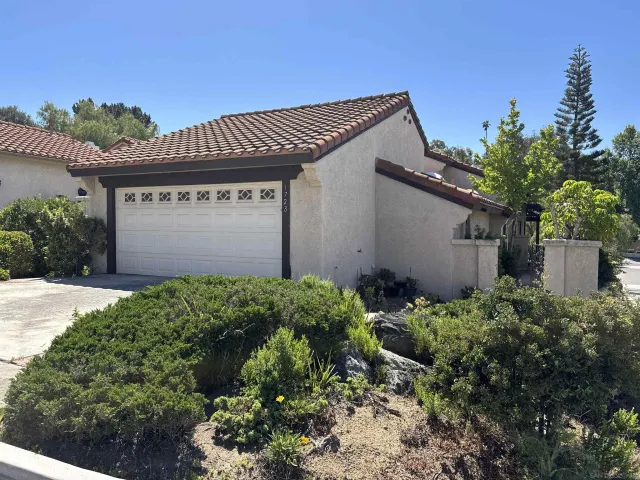 a front view of a house with a garage and plants