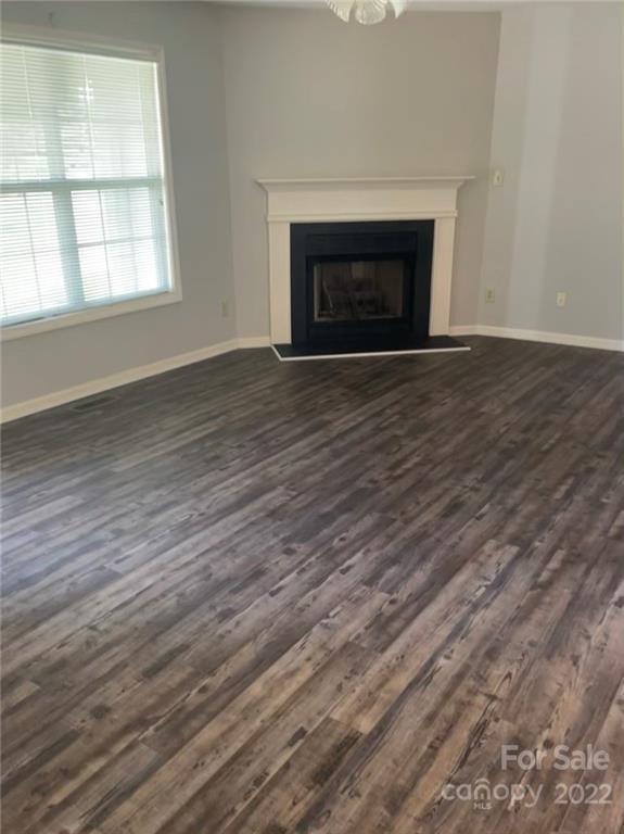 708 Patrick Road Gastonia, NC 28056 - Photo 5 of 15 an empty room with wooden floor fireplace and windows