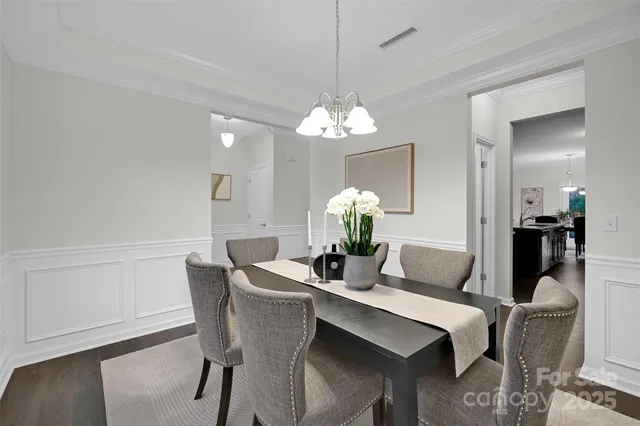 a dining room with furniture a chandelier and wooden floor