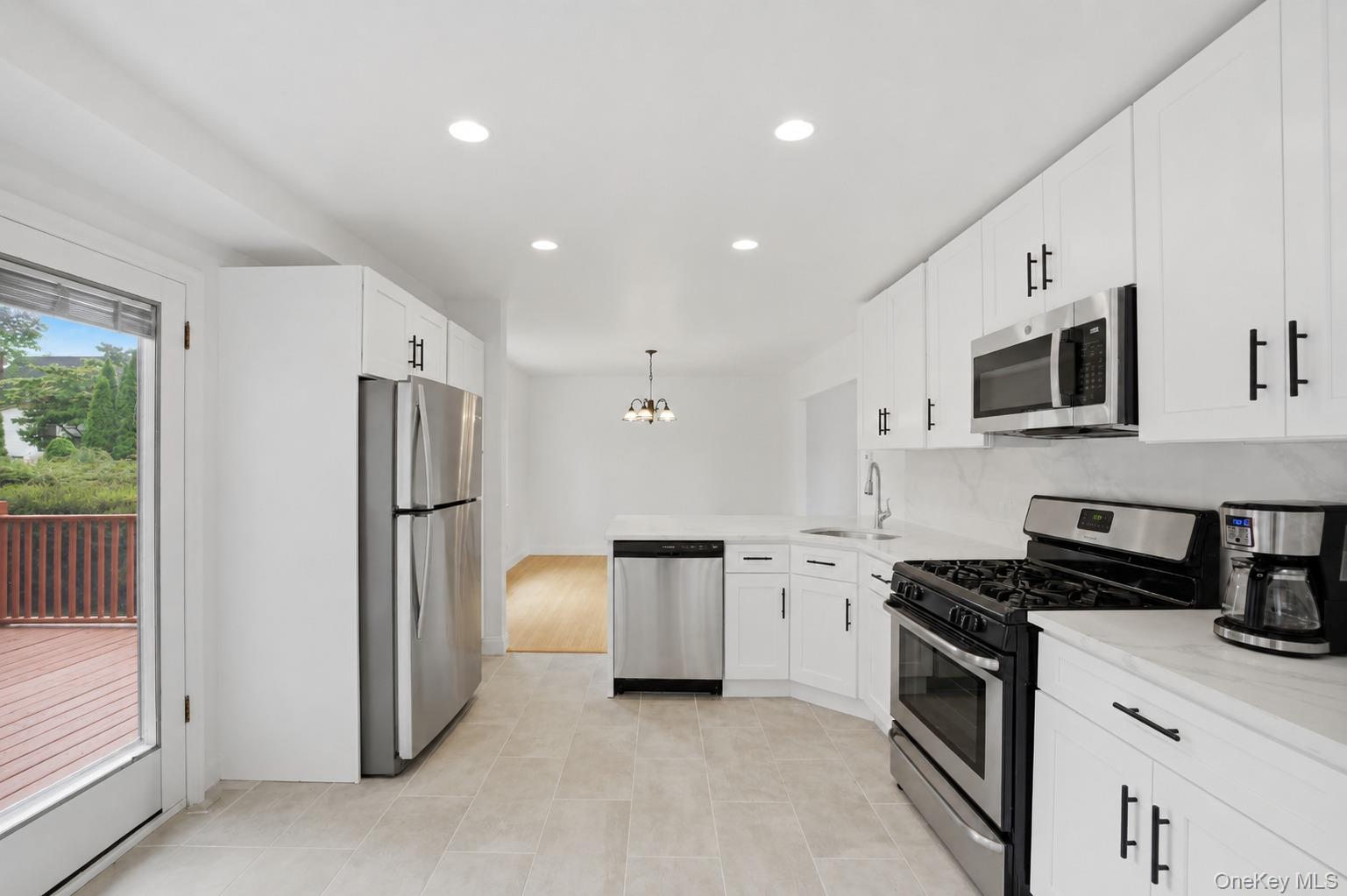 144 Bell Road Scarsdale, NY 10583 - Photo 14 of 49 Contemporary kitchen featuring white cabinetry with black hardware, stainless steel appliances, light-toned countertops, and recessed lighting