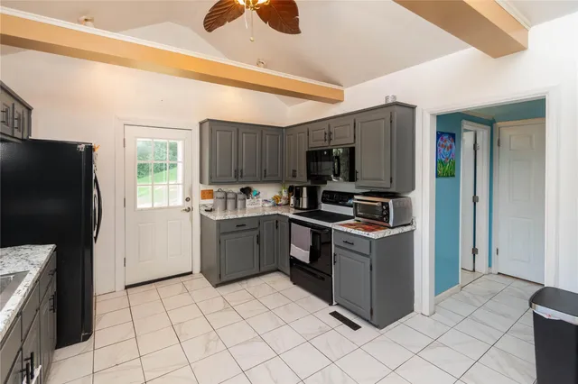 a kitchen with granite countertop a refrigerator and a stove top oven