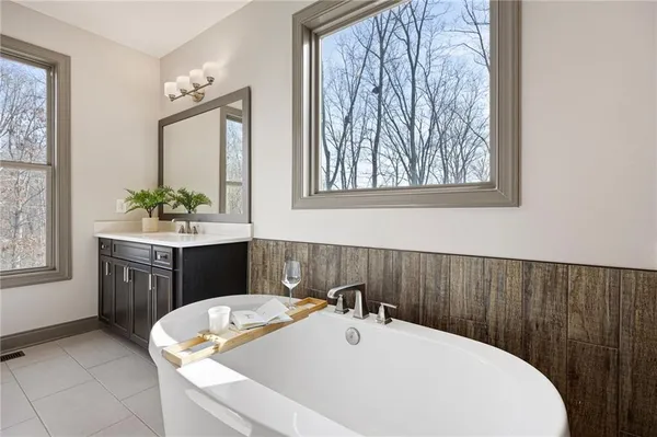 an empty room with windows and view of kitchen