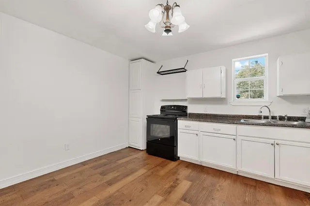 a kitchen with granite countertop a stove a sink and a microwave