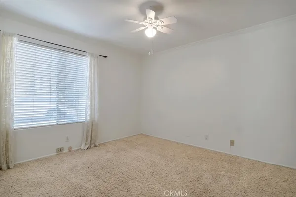 an empty room with a window and a fan
