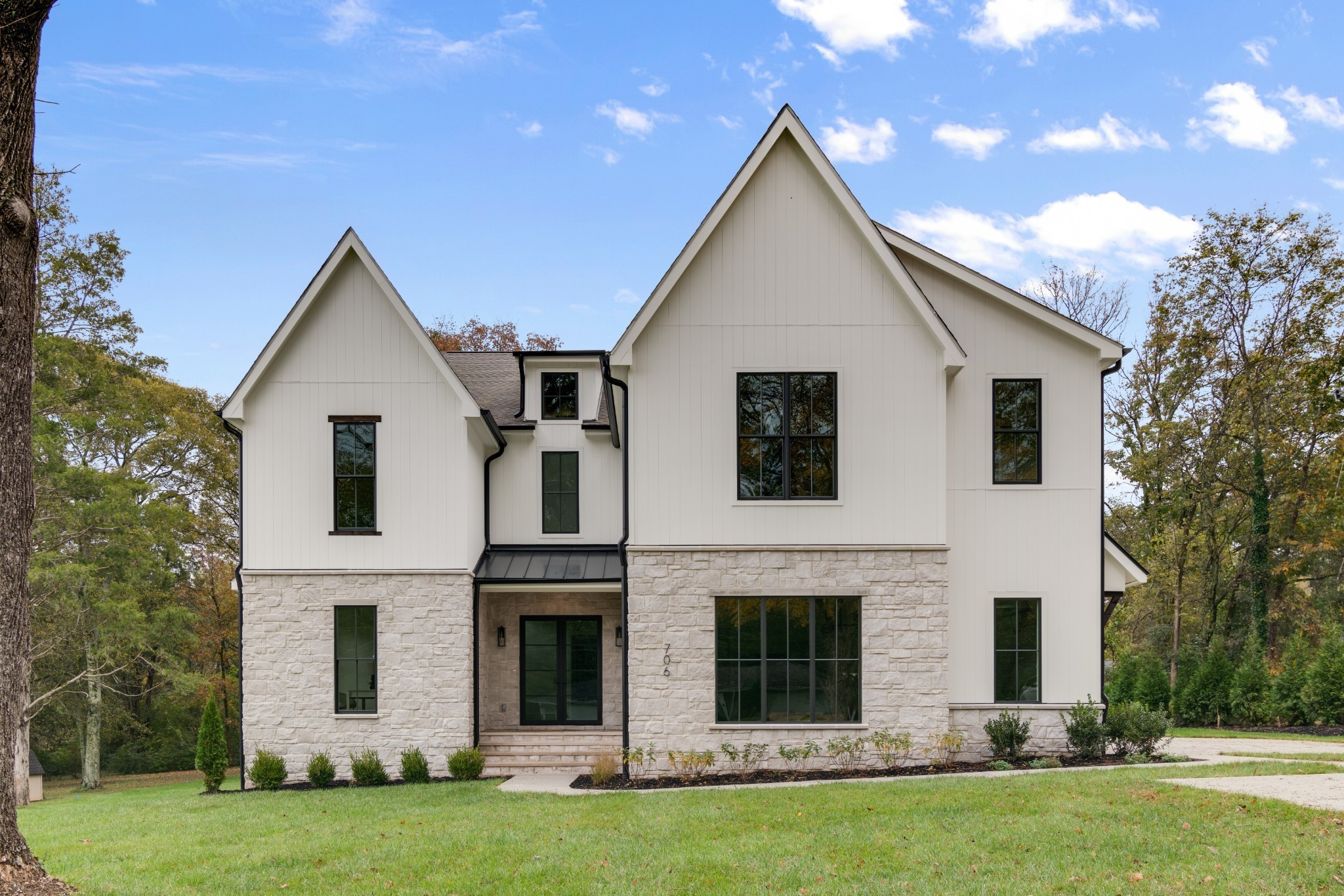 a view of a yard in front of a house with plants and large trees