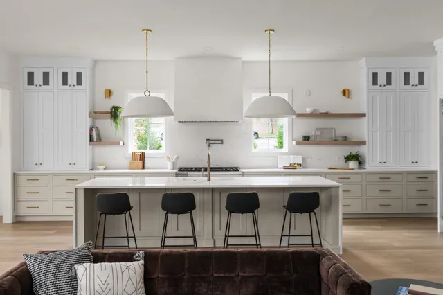 a kitchen with kitchen island granite countertop a sink a stove a dining table and chairs