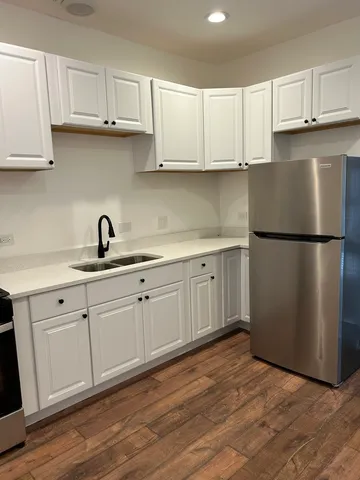 a kitchen with stainless steel appliances granite countertop a refrigerator sink and white cabinets