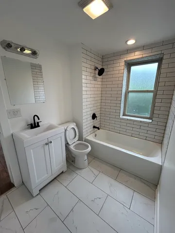a bathroom with a double vanity sink a toilet a mirror and bathtub