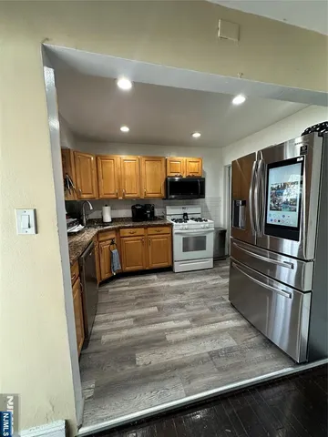 a kitchen with stainless steel appliances granite countertop a refrigerator a stove a sink and a microwave