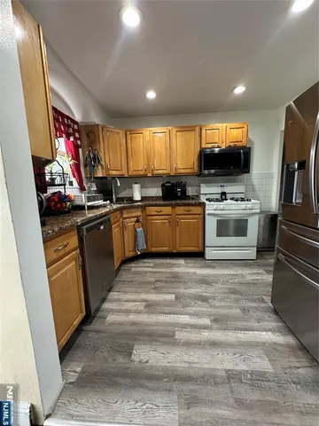 a kitchen with stainless steel appliances granite countertop a stove top oven a sink dishwasher and cabinets with wooden floor