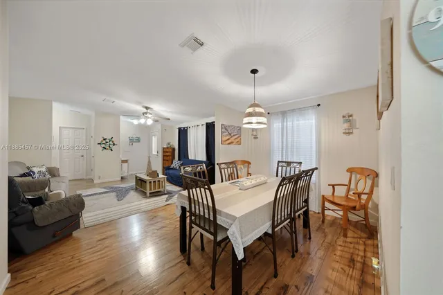 a kitchen with stainless steel appliances kitchen island granite countertop a stove a sink dishwasher a dining table and chairs with wooden floor