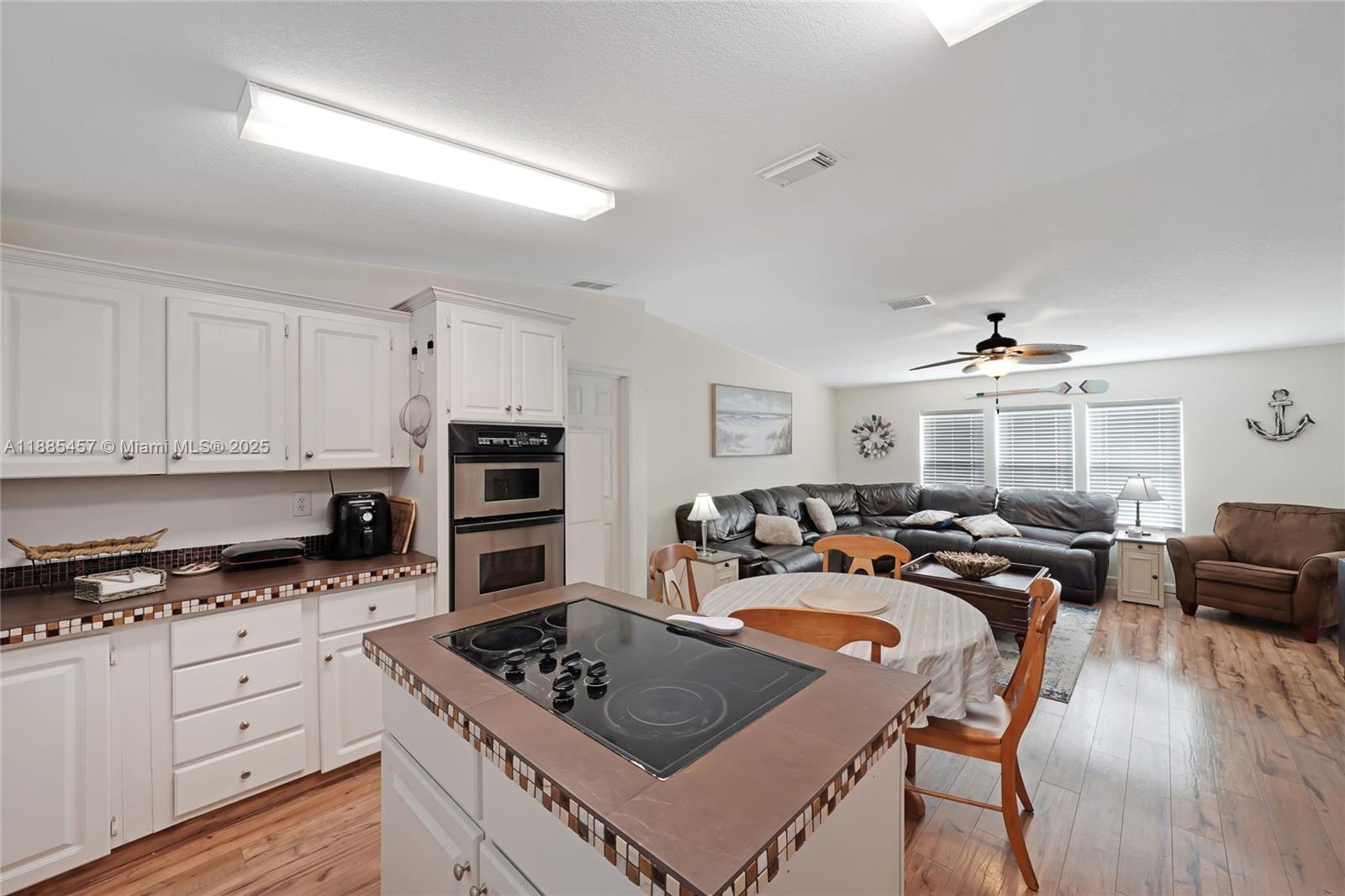 945 Plantation Road, Unit 945 Key Largo, FL 33037 - Photo 9 of 66 a kitchen with stainless steel appliances kitchen island granite countertop a stove a sink dishwasher a dining table and chairs with wooden floor
