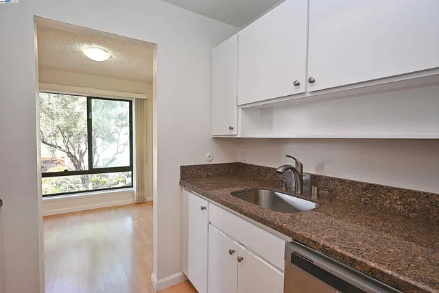 a kitchen with granite countertop white cabinets and a sink
