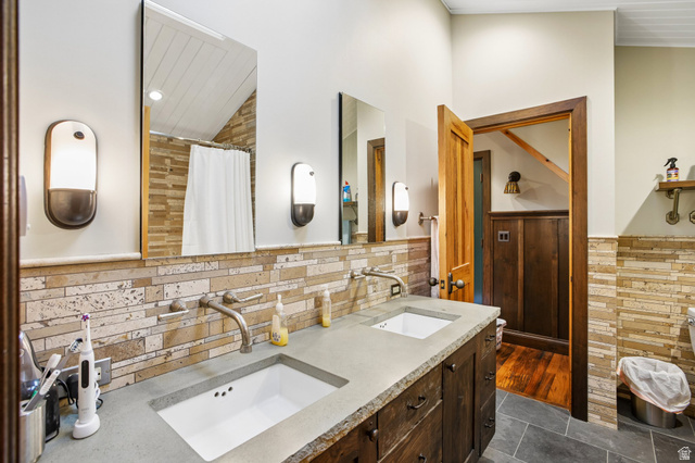 10205 East Moose Loop Road Salt Lake City, UT 84121 - Photo 21 of 50 Bathroom featuring a double vanity with integrated rectangular sinks, stone countertops, and wall-mounted faucets