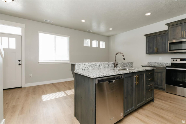 226 South 600 West Logan, UT 84321 - Photo 10 of 25 Kitchen with stainless steel appliances, light stone counters, a kitchen island with sink, light wood-type flooring, and recessed lighting