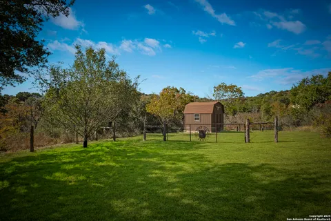 a view of grassy field with benches and trees all around