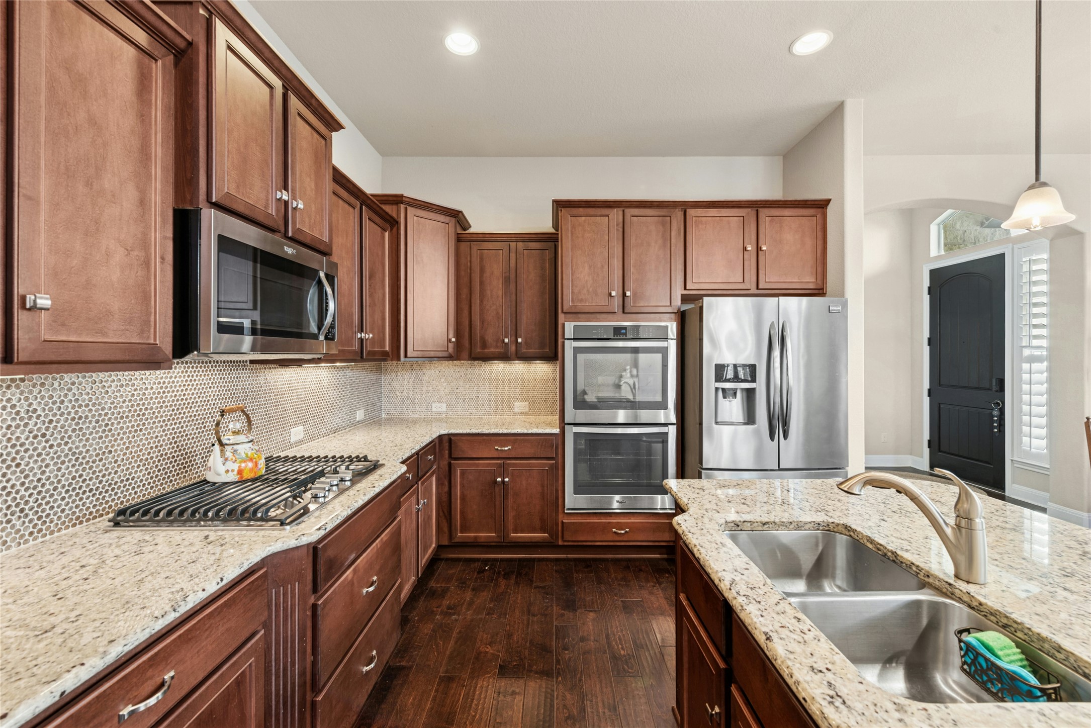 116 Evolutions Path Lakeway, TX 78738 - Photo 9 of 34 Kitchen featuring stainless steel appliances, arched walkways, light stone counters, decorative light fixtures, and dark wood-type flooring