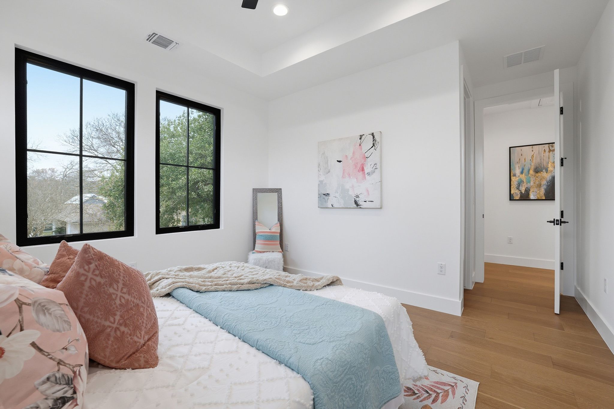 6611 Lexington Road Austin, TX 78757 - Photo 26 of 37 Bedroom featuring two large black-framed windows, a tray ceiling with recessed lighting, and wood-finish flooring
