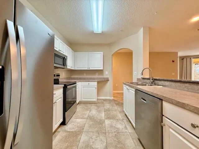 a kitchen with granite countertop a sink stainless steel appliances and cabinets