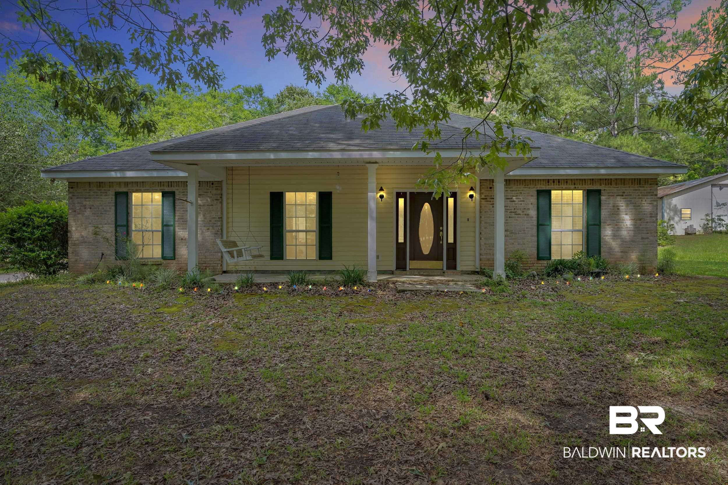 14960 Howells Ferry Road Wilmer, AL 36587 - Photo 1 of 22 Single-story residence featuring a brick and siding exterior, a covered front porch with columns, a prominent front entry door with an oval glass insert and side lights, and decorative window shutters
