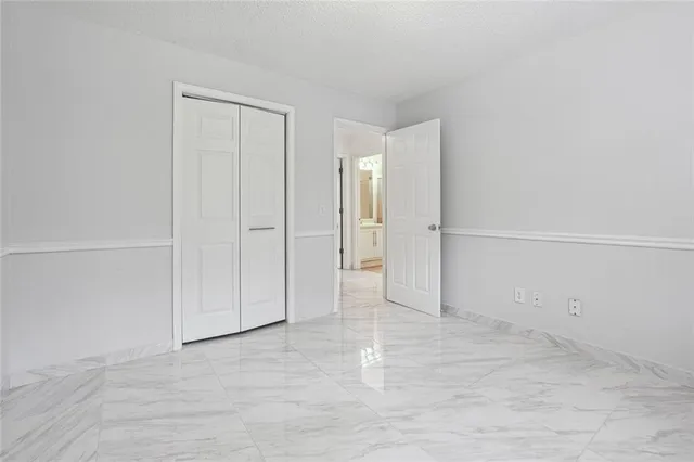 an empty room with windows and chandelier fan