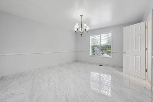 an empty room with wooden floor and chandelier