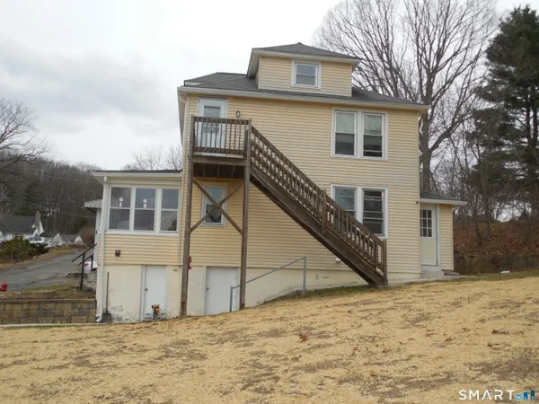 a view of house with wooden fence and a large tree