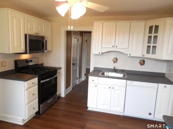 a kitchen with granite countertop a sink stainless steel appliances and white cabinets