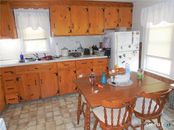 a kitchen with stainless steel appliances granite countertop a sink a stove a refrigerator a dining table and chairs