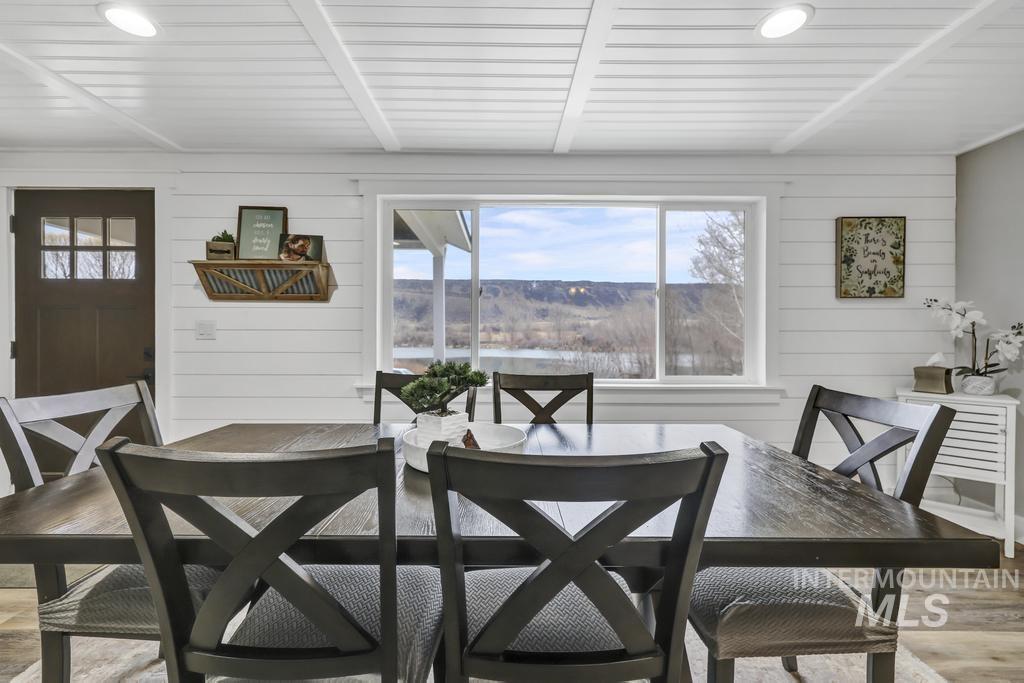 1785 River Road Buhl, ID 83316 - Photo 14 of 41 Dining space featuring wooden walls, light wood-style floors, and beam ceiling