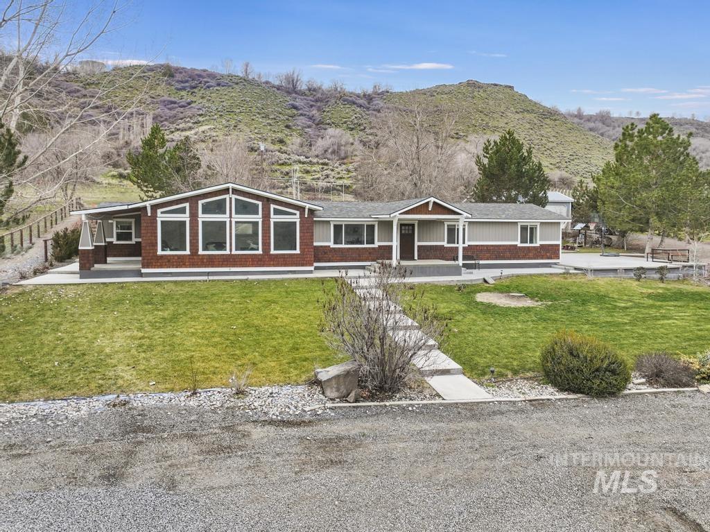 1785 River Road Buhl, ID 83316 - Photo 31 of 41 View of front facade featuring covered porch, a mountain view, a front yard, and brick siding