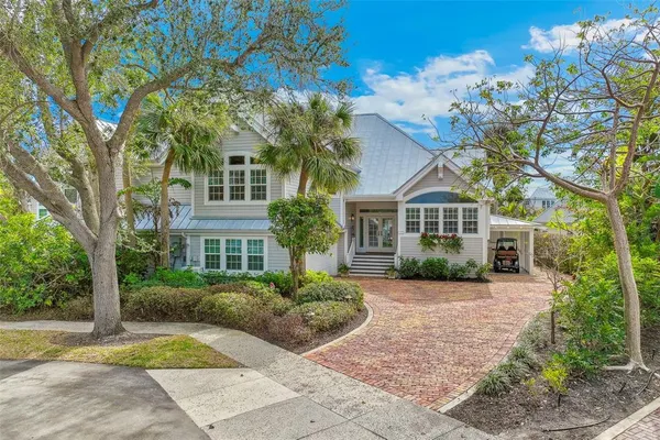 a view of a brick house with a big yard plants and large trees