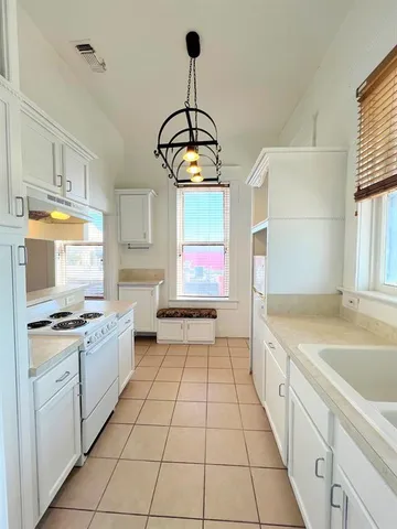 a kitchen with a sink a stove a window and cabinets