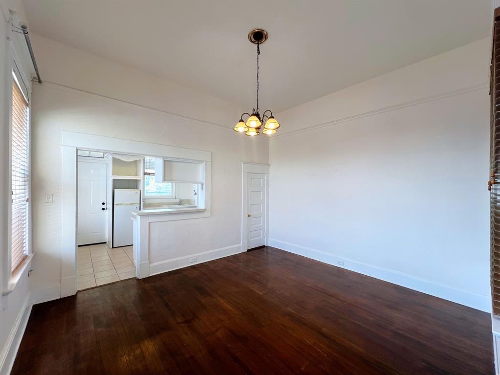 109 Northwest 20th Street, Unit 201 Fort Worth, TX 76164 - Photo 9 of 21 a view of a room with wooden floor chandelier and window