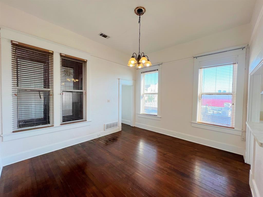 109 Northwest 20th Street, Unit 201 Fort Worth, TX 76164 - Photo 10 of 21 a view of an empty room with wooden floor and a window