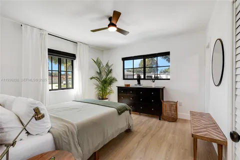 a spacious bedroom with a bed a dresser and a large window