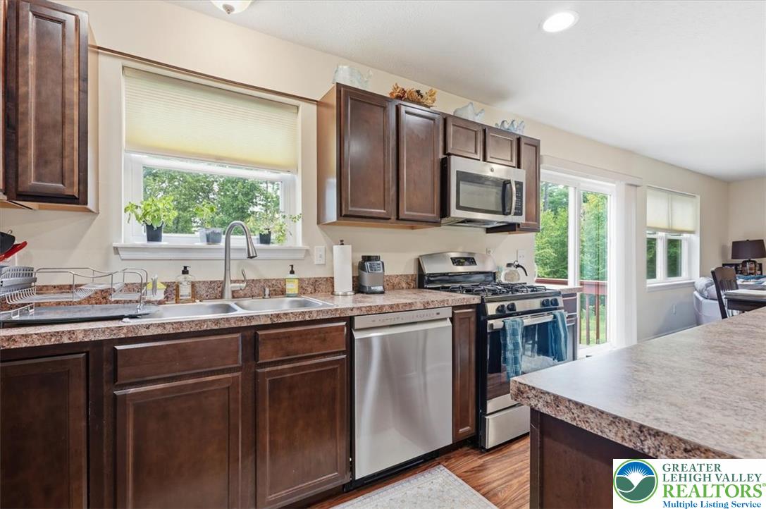 5032 Custard Road Stroudsburg, PA 18360 - Photo 24 of 80 Rich wood cabinetry and stone-look countertops anchor this functional kitchen space.