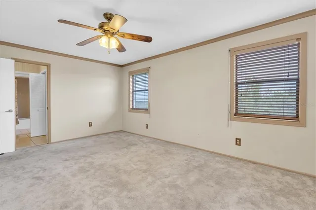 an empty room with ceiling fan and window