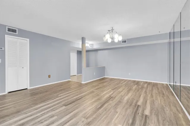 an empty room with wooden floor and chandelier