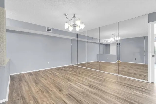 a view of an empty room with wooden floor and a ceiling fan