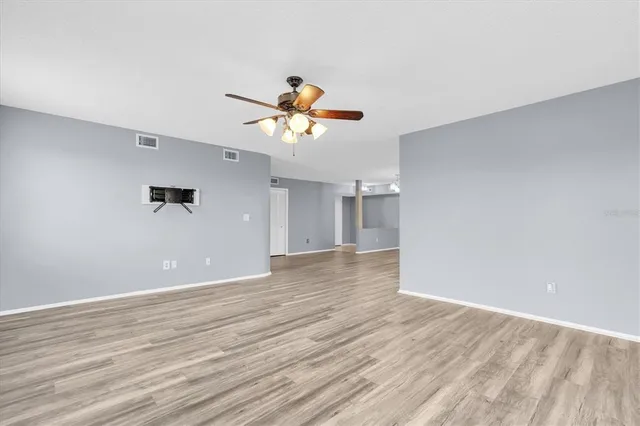 a view of a room with a ceiling fan and wooden floor