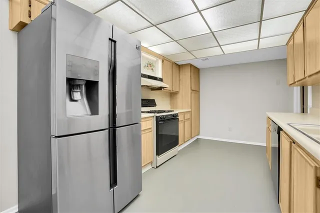 a kitchen with stainless steel appliances granite countertop a refrigerator a oven a sink and white cabinets