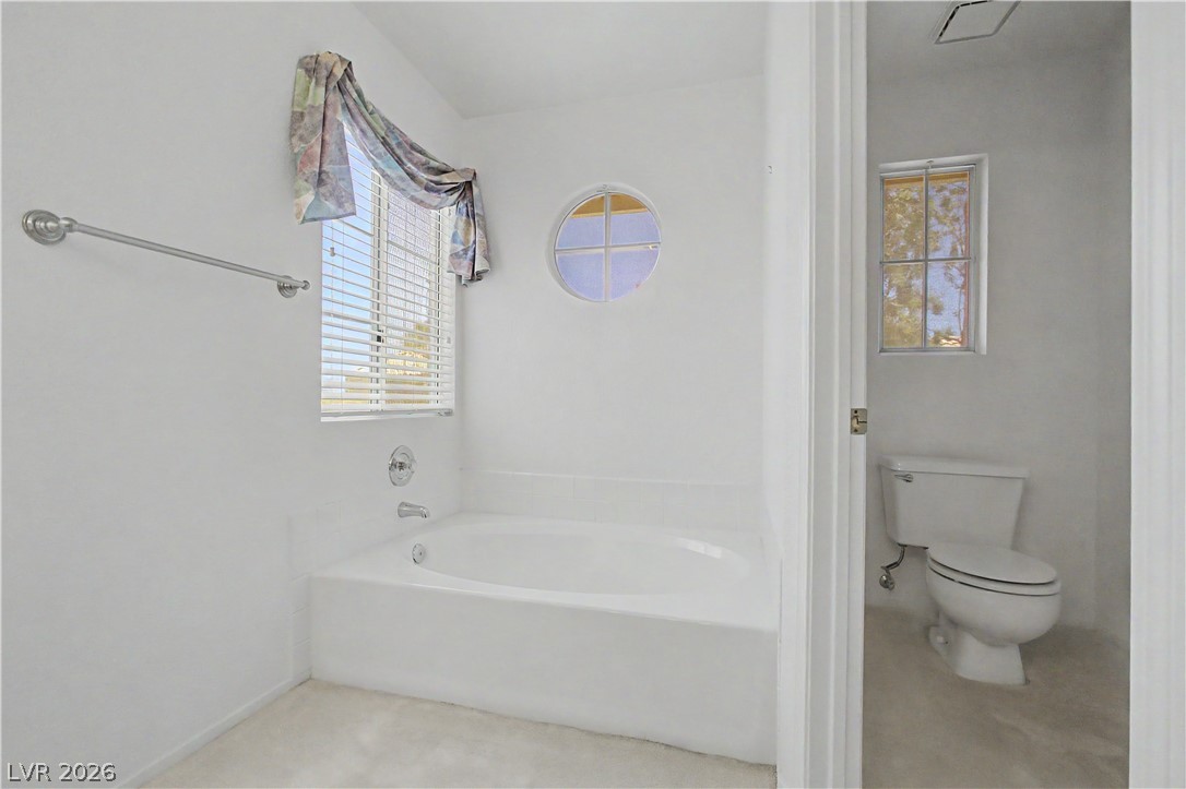 2243 Rugged Mesa Drive Laughlin, NV 89029 - Photo 20 of 32 A deep soaking tub awaits in this sun-drenched bathroom, promising peaceful moments of rejuvenation.