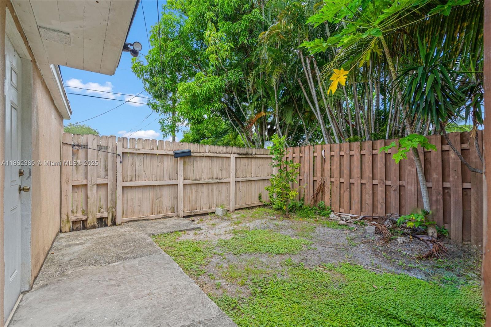 6233 Rodman Street Hollywood, FL 33023 - Photo 27 of 39 a view of a backyard with large trees and wooden fence