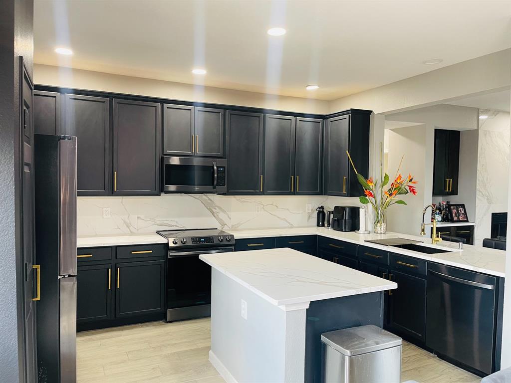 516 Angela Lane Euless, TX 76039 - Photo 12 of 39 Kitchen with appliances with stainless steel finishes, dark cabinetry, light wood-style floors, light stone counters, and recessed lighting