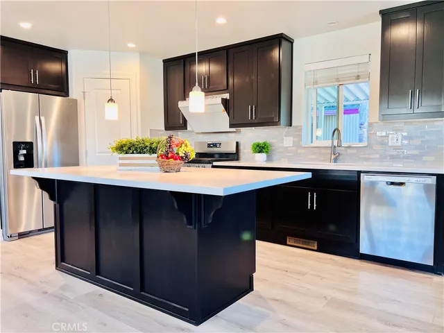 a kitchen with stainless steel appliances kitchen island granite countertop a sink and a refrigerator