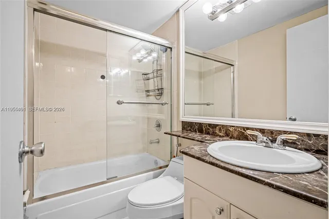 a bathroom with a granite countertop sink toilet a mirror and shower