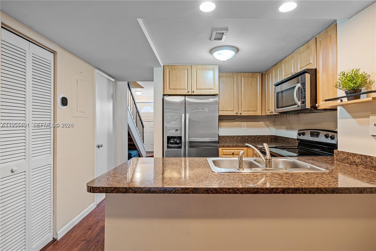 1927 Southwest 107th Avenue, Unit 306 Miami, FL 33165 - Photo 7 of 23 a kitchen with granite countertop a sink a stove and a wooden cabinets