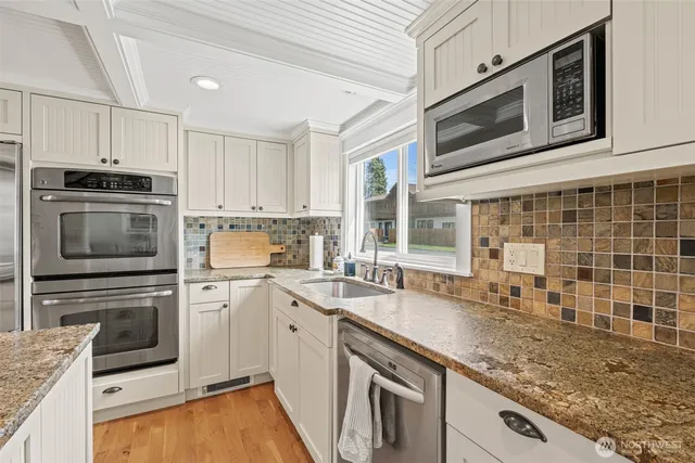 a kitchen with granite countertop a sink a stove and cabinets